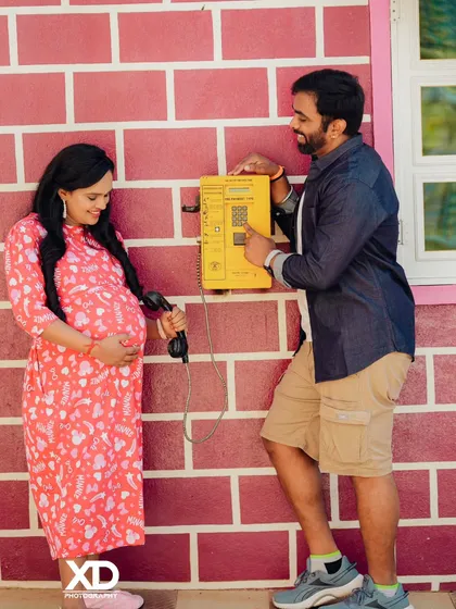 A playful and nostalgic shot of a couple using a vintage yellow payphone as a prop.