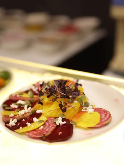 A vibrant beetroot and orange carpaccio salad, layered with crumbled feta and pumpkin seeds. It's a celebration of fresh, seasonal ingredients.