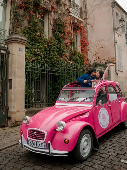 A fun and playful shot of a couple in a bright pink vintage Citroën 2CV on a cobbled Parisian street. This photo is full of personality and captures the charming, whimsical side of the city.