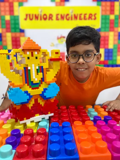 A close-up shot of a smiling student with his impressive, large-scale LEGO Ganesha idol.