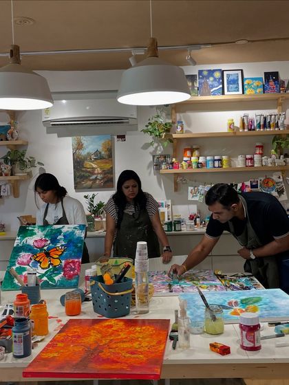 Three artists deeply focused on their large canvases, each working on a colorful and complex piece.