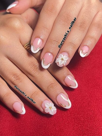 I love adding a touch of luxury to a classic French manicure. Here, I outlined the white tips with a fine gold line and added small 3D flowers for a look that's perfect for an engagement or pre-wedding shoot.