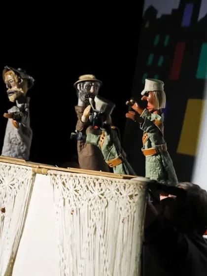 A scene from 'Mamulengo de la Mancha' that combines traditional hand puppets with a shadow-play backdrop, creating a multi-layered visual effect.