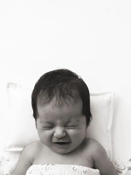 A real, expressive moment from a newborn. Not every photo is a perfect smile, and these authentic expressions are just as precious.