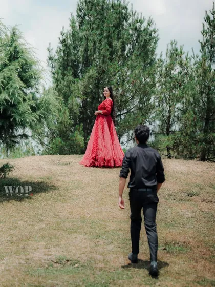 A creative shot where the man walks towards the woman, who stands on a small hill, creating a sense of journey and connection within the beautiful Himachali landscape.