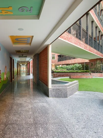 A school corridor that opens to a central green courtyard. This demonstrates our strategy of incorporating natural elements and open spaces to boost learning and well-being in urban educational settings.