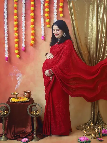 The flowing red saree against a warm, glowing backdrop creates such a dreamy and powerful image. The smoke from the diya adds a touch of sacred magic to this maternity portrait.