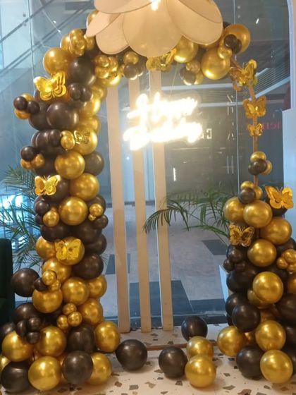 A chic black and gold balloon arch, perfect for an elegant birthday celebration in a cafe or restaurant. I added gold butterfly accents and a "Happy Birthday" neon sign to complete this sophisticated look.