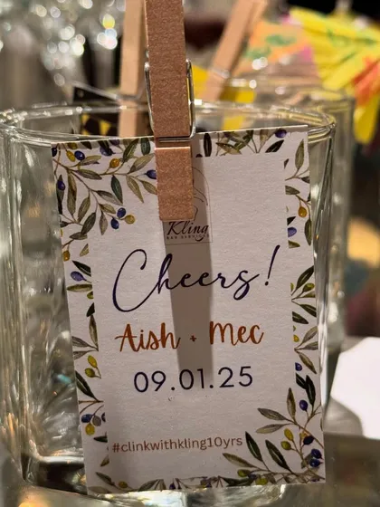 A close-up of the personalized glass tag for Aish & Mec's celebration, featuring a lovely olive branch design.