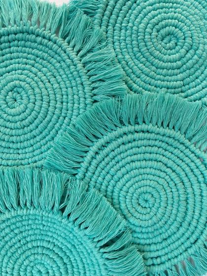 Another perspective on the set of turquoise coasters, showing how they stack and overlap. The fringed edges add a soft, playful detail to the design.
