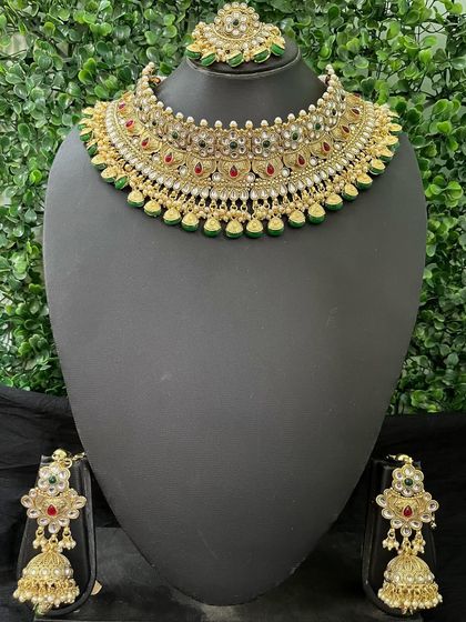 A classic rental choker set with red and green stones. The traditional design and matching jhumkas make it a timeless choice for any bride.