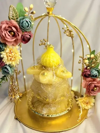 A creative way to present smaller gifts in a trousseau. This golden birdcage platter, decorated with flowers and fairy lights, turns a simple gift into a stunning decorative piece.