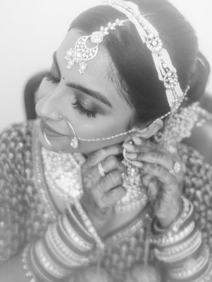 A black and white close-up of a bride putting on her earring, a classic getting-ready shot.
