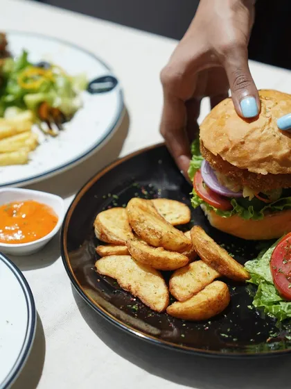 The perfect grip on a juicy burger, showing the layers of fresh ingredients packed inside a soft bun.