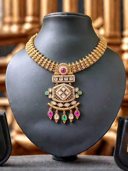 A stunning temple-style necklace set with a rich gold finish and colorful stone accents, complete with matching jhumkas.