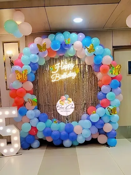 A colorful butterfly-themed balloon ring with a shimmer curtain and marquee number '5'.