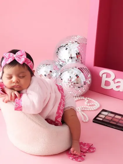 A little diva in dreamland. This Barbie-themed newborn shoot is full of fun and glamour. Here, our little model is styled with a tiny robe and accessories for a playful and fashionable portrait.