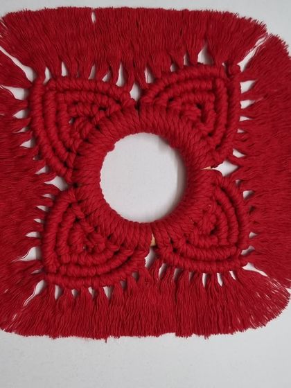 The red diya holder without the candle, showcasing the intricate knotwork and central opening.