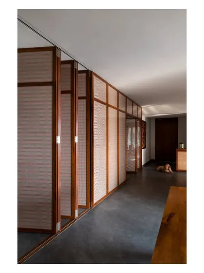 These space-transforming shutters, made of teak and woven cane, can be pivoted or folded away to control light and privacy along the length of the corridor.