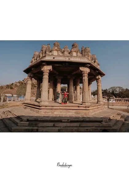 An expansive view of a couple standing within a pillared gazebo at a heritage site, emphasizing the architectural beauty and the scale of the location.