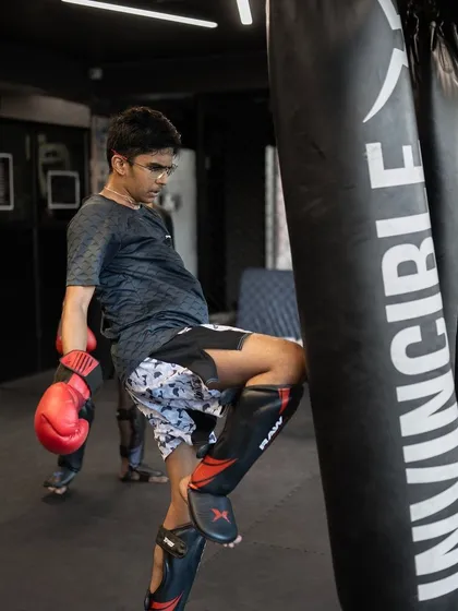A young fighter works on his teep, or push kick, on the heavy bag. This is a crucial tool for controlling distance in a fight.