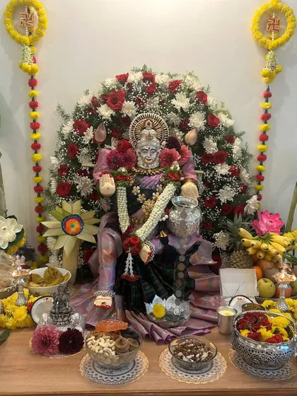 This deity is draped in a soft mauve silk saree, surrounded by an arch of red and white roses for the festival.