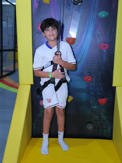 Suited up and ready to climb. We ensure every child is securely fitted with a safety harness before they take on our climbing wall, making the adventure both thrilling and safe.