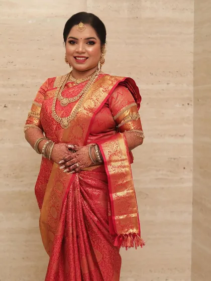 A South Indian bride in a rich red silk saree, looking radiant and happy.
