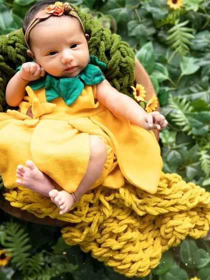 Capturing the delicate innocence of a newborn is my greatest passion. In this newborn portrait, I used soft, natural elements like this sunflower-themed wrap and lush greenery to create a peaceful, organic setting for this one-month-old darling.