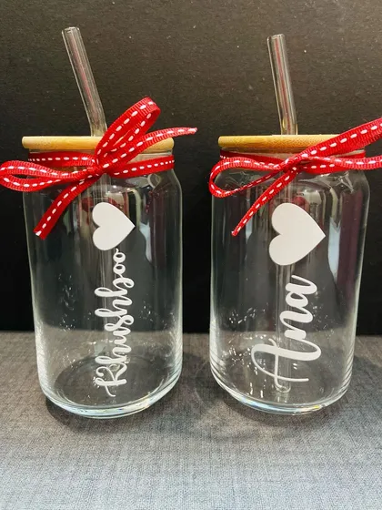 A pair of our can-shaped glass tumblers, personalised with names and a heart. The red ribbon adds a festive touch, making them ready for gifting.