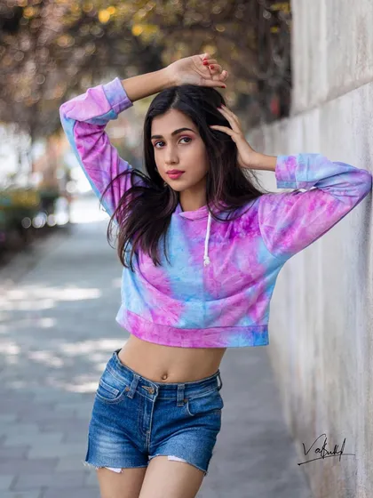 A relaxed and stylish portrait from a street fashion series. The tie-dye hoodie adds a pop of color, and the model's pose against the wall feels natural and effortlessly cool.