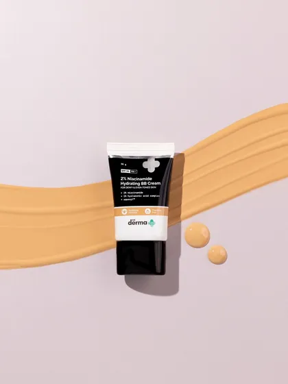 A simple, elegant composition. A single, clean smear of BB cream creates a path for the eye, leading directly to the product tube. The small drops add a final touch of detail.