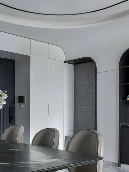 The dining and storage area in 'The House of Arcs' features custom cabinetry with arched niches, continuing the home's central design theme.