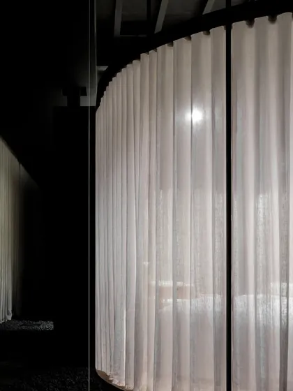 A close-up view highlights the ephemeral quality of the sheer curtains. This material choice was critical for its ability to filter and soften light, lending a sense of transparency and quiet elegance while defining the boundaries of the space.