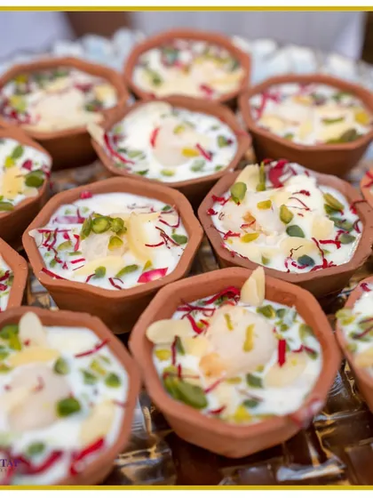 A refreshing and beautiful dessert featuring litchi and rabri, served in traditional clay kullads and garnished with saffron, pistachios, and rose petals.