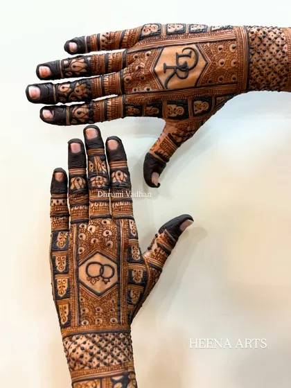 This engagement mehendi features the couple's initials 'R' and 'D' on the back of the hands, along with a symbol of intertwined rings. It’s a chic and modern way to personalize your henna.