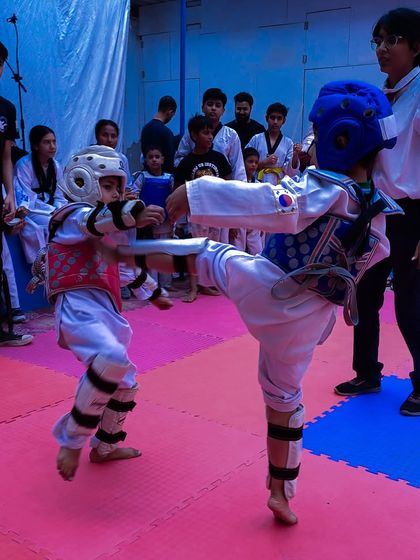 Two young competitors face off during the 1st Strike Inter-Club Tournament, demonstrating their kicking skills in a controlled match.