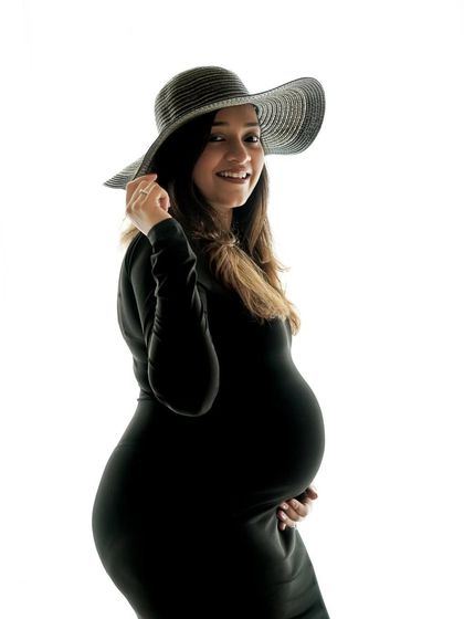 A stylish solo portrait in a black dress and wide-brimmed hat, exuding confidence and grace.