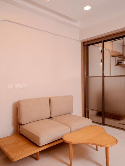 A compact seating area with a custom wooden sofa and organic-shaped coffee table, demonstrating our ability to create functional and stylish minimalist furniture.