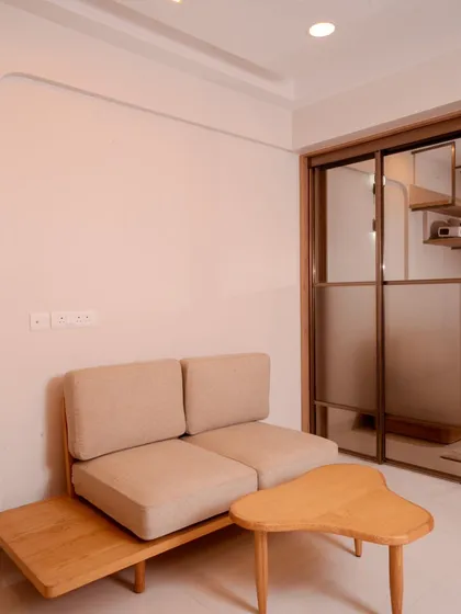 A compact seating area with a custom wooden sofa and organic-shaped coffee table, demonstrating our ability to create functional and stylish minimalist furniture.