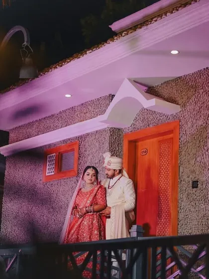 A full-length shot of the couple outside their wedding venue at night. The ambient lighting creates a romantic and slightly dramatic mood for this portrait.