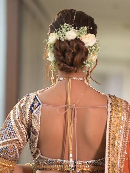 A detailed shot of the twisted floral bun, showing the beautiful texture of the hair and the fresh flowers. This is a perfect look for a grand wedding celebration.