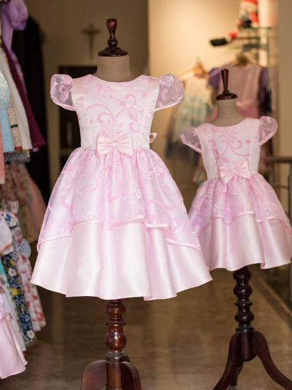 A side-by-side view of the matching pink organza gowns. The puff sleeves and layered skirt create a classic princess silhouette that little girls adore.