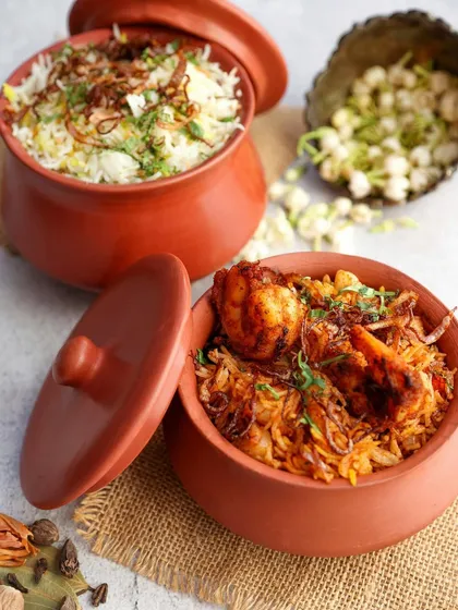 Aromatic prawn and vegetable biryanis served in traditional clay handis, styled with fresh jasmine flowers for an authentic touch.