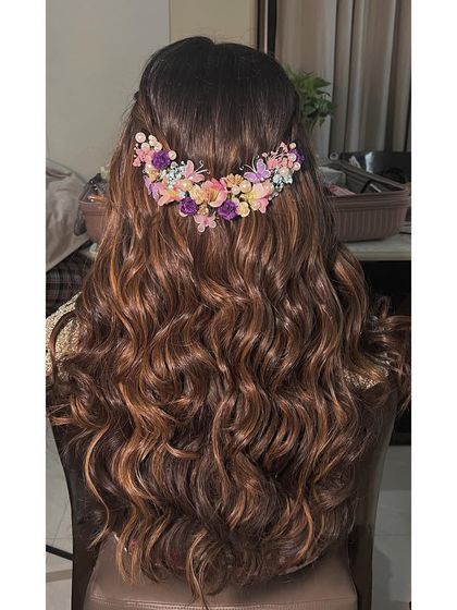 A back view of the engagement hairstyle, showing the intricate placement of the pastel floral hairpiece. It adds a beautiful pop of color to the soft waves.