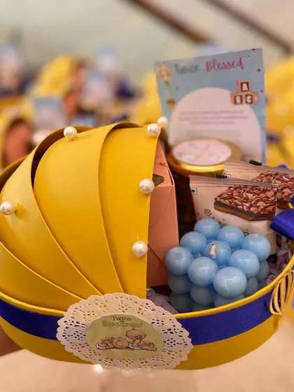 Announcing the arrival of a little one with our adorable baby cradle hamper. This uniquely shaped yellow and blue basket is filled with goodies like a bubble candle and sweet treats, making it a memorable baby announcement gift.