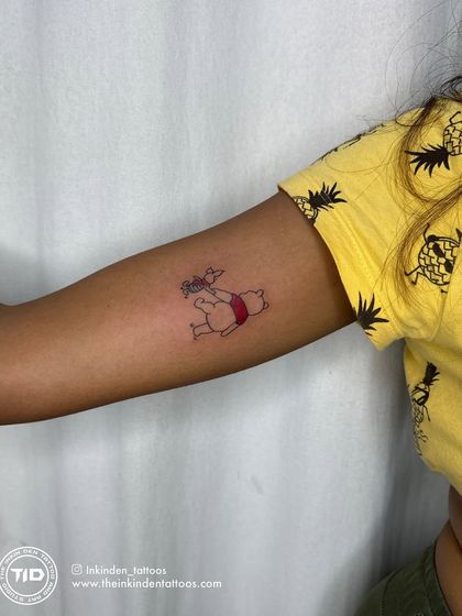 The finished Winnie the Pooh and Piglet tattoo, shown on the client's arm.