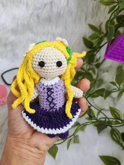 Disney Princess Rapunzel, with her long, flowing yellow hair decorated with flowers. Her purple dress is detailed with corset lacing, just like in the movie Tangled.