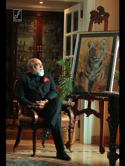 An environmental corporate portrait of a senior executive in a richly decorated office, sitting next to a piece of art. This style of portrait tells a story about the person's status and taste.