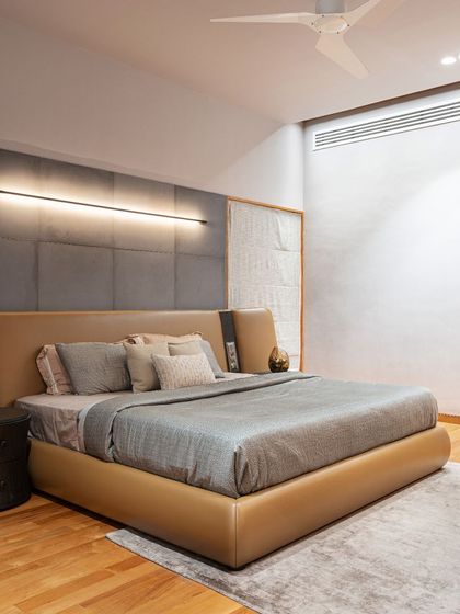 Another bedroom in the residence, featuring a custom-designed bed with a unique leather and fabric headboard. A sleek, linear wall light provides ambient illumination.
